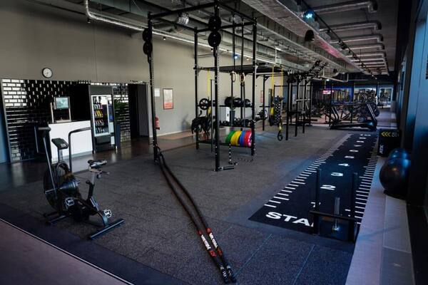 Moderner Fitnessraum mit Krafttraining-Racks, Laufbahn und Trainingsgeräten